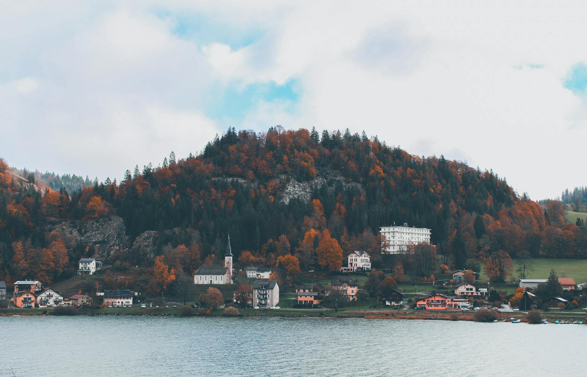 Jesienna wieś nad jeziorem z kolorowymi drzewami i spokojną wodą