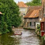 Kanał w Brugii z łodzią wycieczkową i zabytkowymi kamienicami