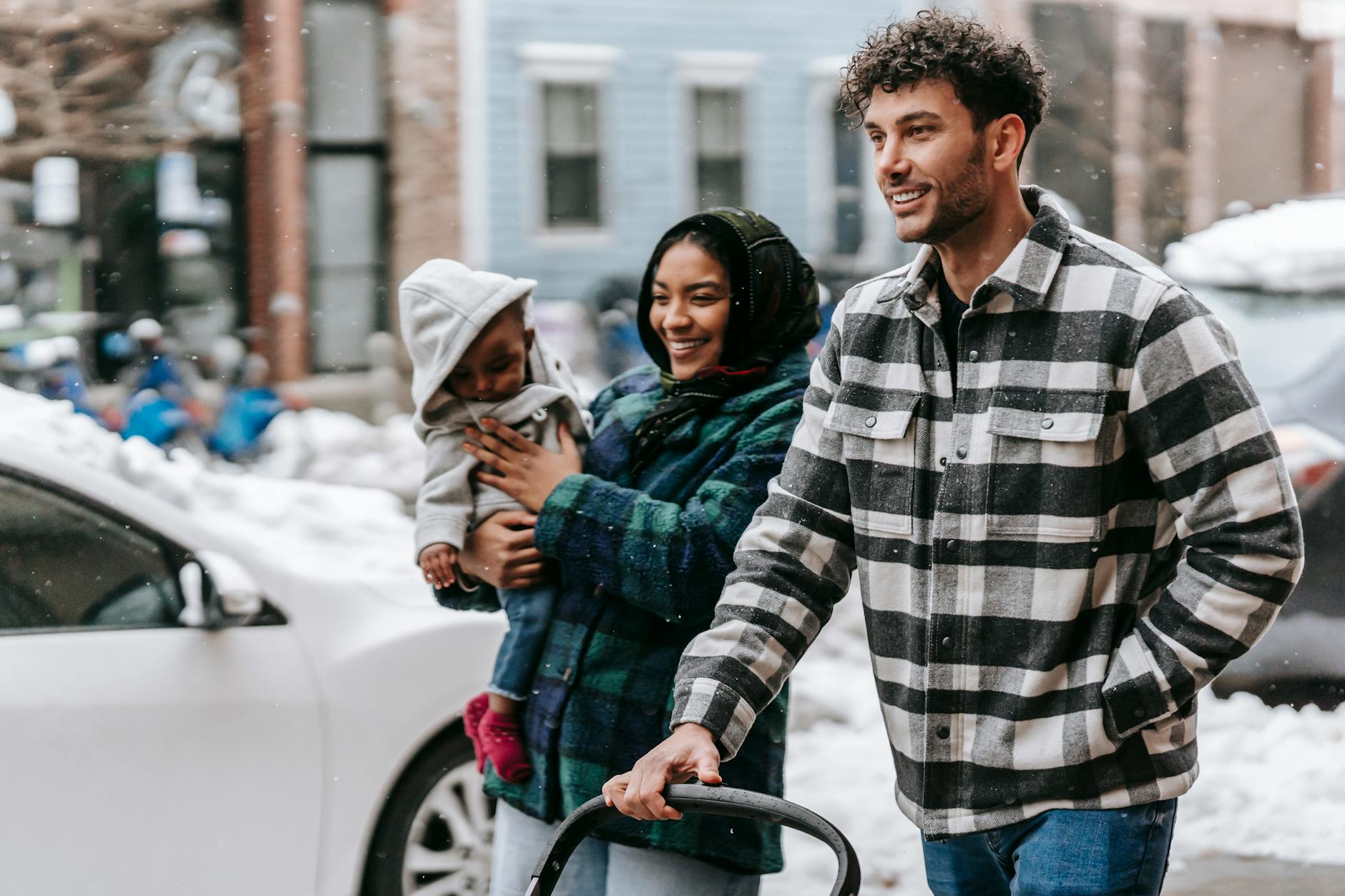 Rodzina z małym dzieckiem spaceruje zimą po ośnieżonych ulicach Ostrowa