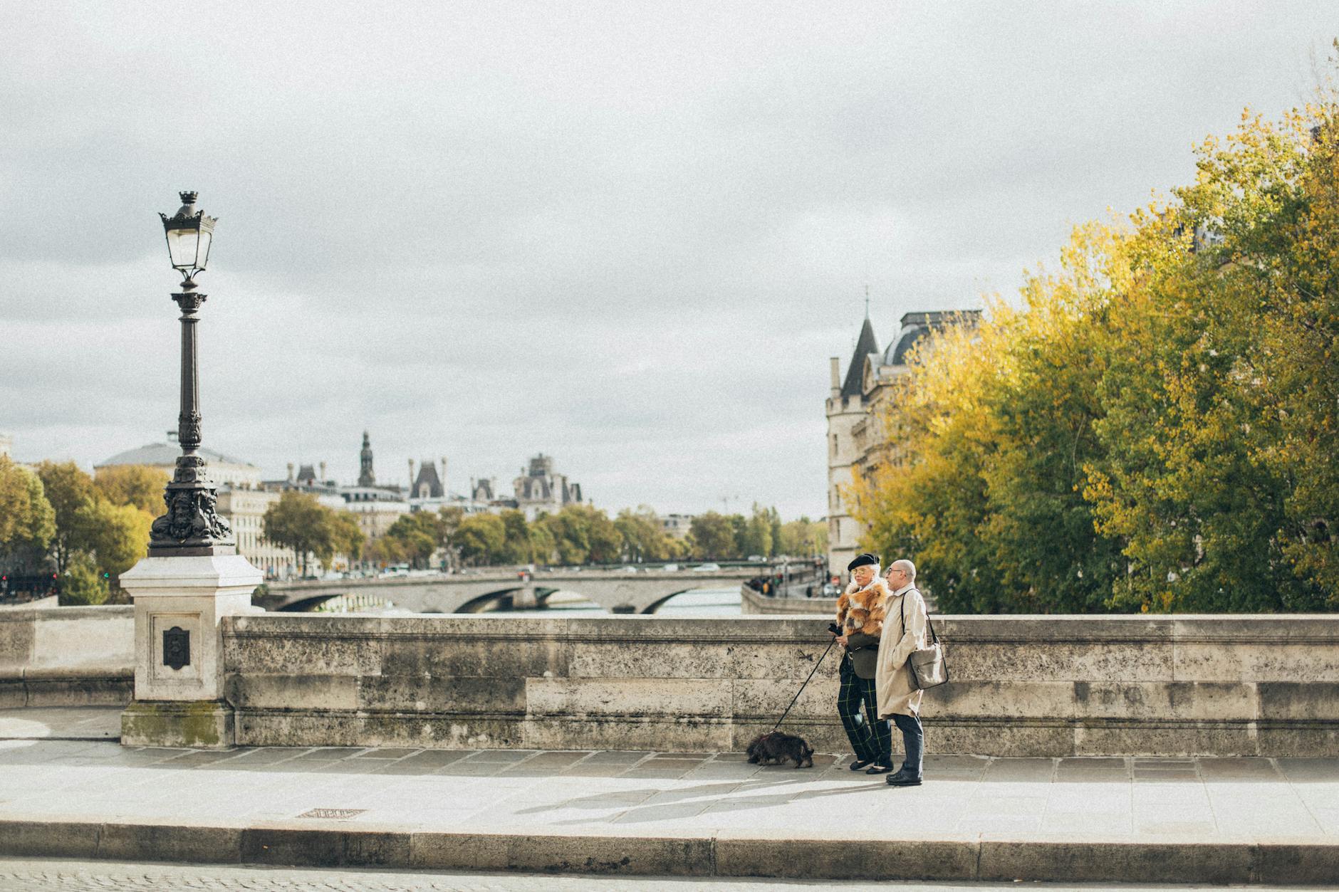 Starsze małżeństwo spaceruje z psem po miejskim moście