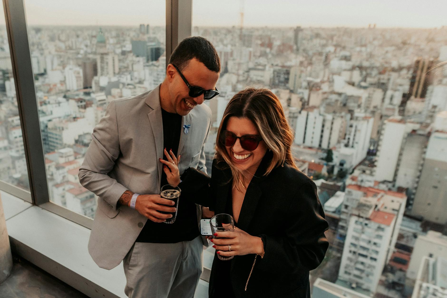 Zakochana para z drinkami na dachu kamienicy z widokiem na miasto o zmierzchu