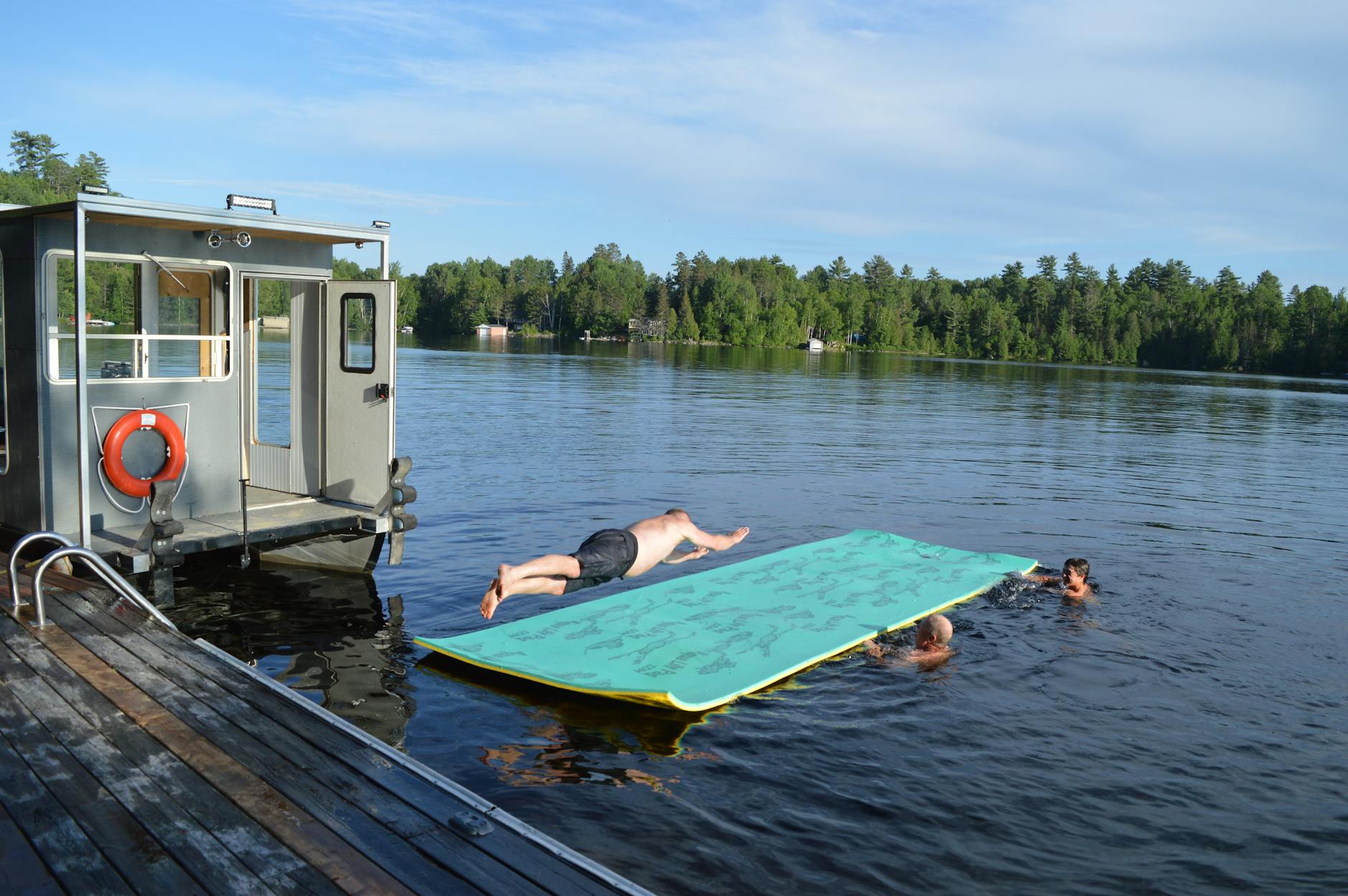 Dorośli relaksują się na jeziorze latem na pływającej macie obok domku