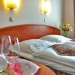 Noclegi w Pile: sprawdzone miejscówki na krótki i dłuższy pobyt Elegancki pokój hotelowy w Pile z łóżkiem, winem i kwiatami