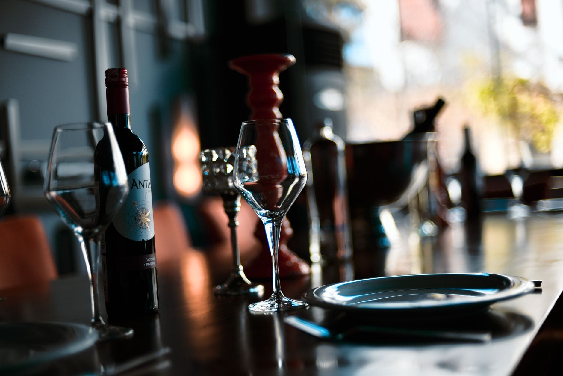 Kieliszki i butelka wina w nastrojowo oświetlonym wnętrzu restauracji