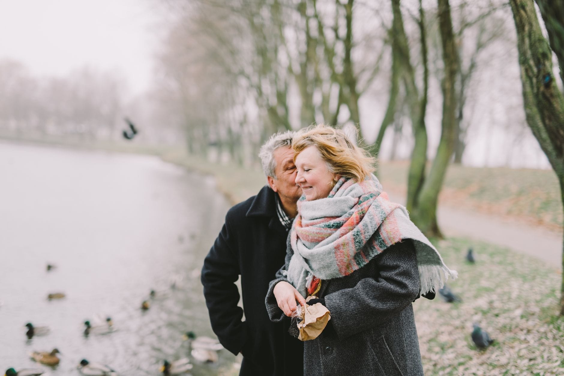 Para seniorów spaceruje zimą nad jeziorem