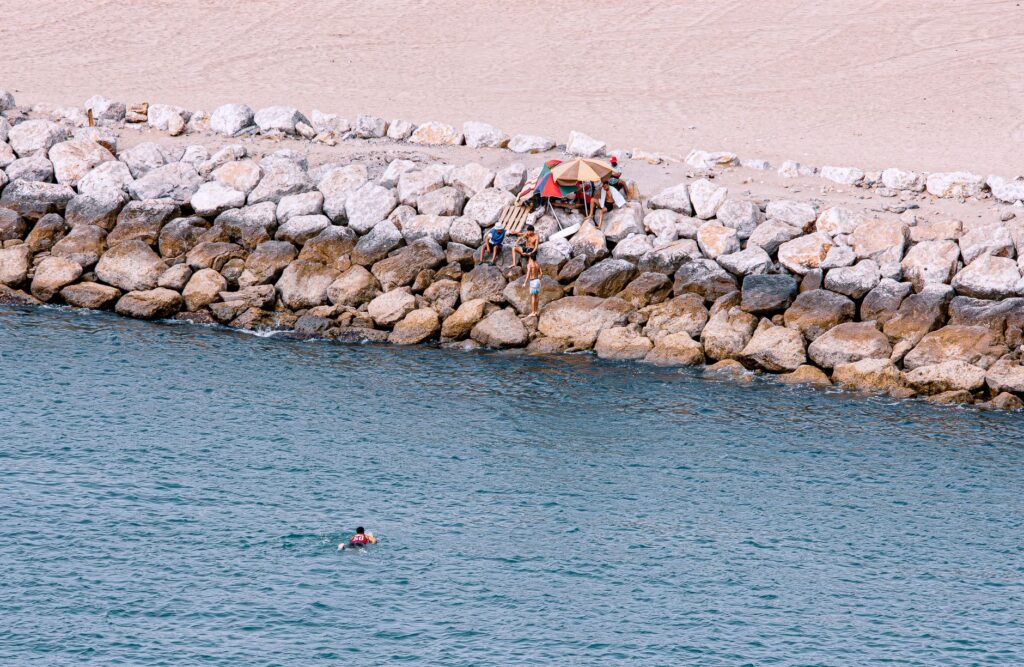 Widok z góry na ludzi wypoczywających na kamienistej plaży nad turkusową wodą